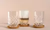 Three glasses on a light pink background, one filled with a layered coffee drink. Anteprima dell’immagine prodotto