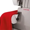 A close-up shot of a red fabric being fed into a Singer sewing machine. Náhľad obrázku produktu