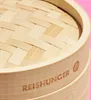 A close-up view of a bamboo steamer lid and rim, with the brand name 'REISHUNGER' visible. Produktbild-Vorschau