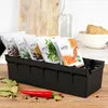 A black spice organizer filled with spice packets, placed on a wooden surface with bay leaves and a chili pepper in the foreground. Voir les images du produit