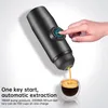 A hand presses a button on a portable espresso machine as coffee dispenses into a glass cup. Náhled obrázku produktu