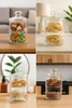 A collage of four images showing a two-tiered glass jar filled with different items in various settings. Produktbild-Vorschau