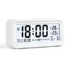 A white digital alarm clock is shown against a white background. The clock displays the time, date, temperature, and humidity. Produktbild-Vorschau
