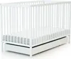 A white baby crib with a mattress and a pull-out drawer underneath, shown from a diagonal angle. Voir les images du produit