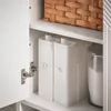 Interior view of a white cabinet with shelves, showing storage containers and a basket. Voir les images du produit