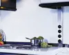 A close-up view of a kitchen countertop with a stovetop, a pot of artichokes, and a vertical power strip with multiple outlets. Produktbild-Vorschau