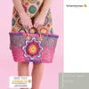 A person holding a crocheted bag with a colorful floral motif. Produktbild-Vorschau
