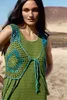 A woman wearing a crocheted vest over a green dress in an outdoor, arid environment. Produktbild-Vorschau