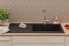 A black kitchen sink with a faucet, a plant, and some food items on a countertop. Produktbild-Vorschau