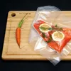 A vacuum-sealed salmon fillet with lemon and dill next to a carrot on a wooden cutting board. Produktbild-Vorschau