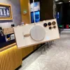 A phone case with a magnetic charger attached, displayed in what appears to be a cafe or restaurant setting. Náhled obrázku produktu