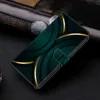 A close-up, angled view of a dark green wallet-style phone case with gold accents, resting on a dark textured surface. Produktbild-Vorschau