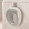 A child's toilet seat is hanging on a hook on a wall. Produktbild-Vorschau