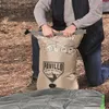 A person kneeling on the ground, holding a deflated air mattress. Podgląd zdjęcia produktu