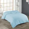 A light blue duvet is laid out on a bed in a room with a large window and a bedside table. Produktbild-Vorschau