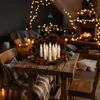 A Christmas wreath with LED candles on a wooden table, with a fireplace and Christmas lights in the background. Náhled obrázku produktu