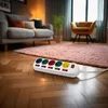 A power strip with multiple outlets and individual switches is placed on a wooden floor in a living room setting, with a sofa and armchair in the background. Produktbild-Vorschau