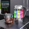 A glass kettle with LED lighting and a separate glass infuser on a countertop. Voir les images du produit