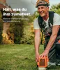 A man wearing safety gear is kneeling in a grassy yard, holding a piece of landscaping equipment. Anteprima dell’immagine prodotto