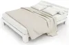 A white wooden bed frame with a mattress, duvet, and pillows, shown from a diagonal angle on a white background. Náhled obrázku produktu