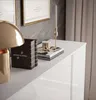 A close-up view of a white, high-gloss dresser with gold accents, featuring decorative items on its surface. Produktbild-Vorschau