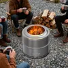People sitting around a fire pit in an outdoor setting, holding mugs. Produktbild-Vorschau
