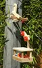 A wooden pulley system with a small basket attached, mounted on a wooden post and surrounded by green foliage. Produktbild-Vorschau