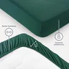 A close-up view of a dark green fitted sheet, showing its elastic edge and some text overlays highlighting product features. Produktbild-Vorschau