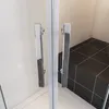 Close-up view of a modern shower enclosure with chrome handles and black tiled floor. Produktbild-Vorschau