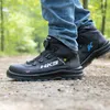 A person wearing HKS safety boots walks on a dirt path in a wooded area. Produktbild-Vorschau
