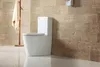 A white toilet with a tank is shown in a bathroom with tiled walls and a light-colored floor. A towel hangs on a wooden rack to the left. Produktbild-Vorschau