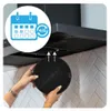 A person is holding a round black charcoal filter in front of a kitchen range hood. Produktbild-Vorschau