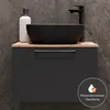 A modern bathroom vanity with a black sink and faucet against a dark tiled wall. Produktbild-Vorschau