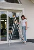 A woman is standing next to a ladder in front of a large window. Anteprima dell’immagine prodotto