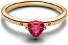 A close-up studio shot of a gold ring with a heart-shaped pink gemstone. Produktbild-Vorschau