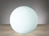 A white sphere on a tan surface with a gray gradient background. Produktbild-Vorschau