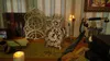 A desk with steampunk-themed decorative items, including a wooden owl clock, books, a vintage telephone, and candles. Produktbild-Vorschau
