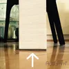 Close-up of the base of a furniture piece on a wooden floor, with a glass cabinet in the background. Produktbild-Vorschau