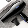 A black hairdryer with a blue button is placed on a textured gray surface next to a black styling nozzle. Produktbild-Vorschau