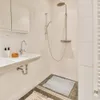 A clean and modern bathroom with a sink and a shower. Náhľad obrázku produktu