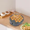 A takoyaki maker with freshly made takoyaki balls, next to a salad and grilled chicken. Náhled obrázku produktu