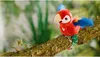 A plush parrot toy perched on a tree branch in a natural setting. Produktbild-Vorschau