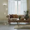 A living room scene with a floral sofa, coffee table, and a floor lamp. Produktbild-Vorschau