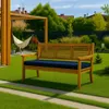 A wooden bench with a blue cushion sits on a green lawn in a backyard setting, with a hammock and pergola in the background. Produktbild-Vorschau