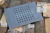 A metal grate with holes is placed on a pile of firewood. Dimensions and model information are overlaid on the image. Náhled obrázku produktu