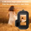 A person is walking in a field, and a small digital camera is in the foreground. Produktbild-Vorschau