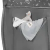 A close-up view of a grey fabric pocket on the side of a baby travel cot, containing a stuffed toy, a bib, and a blanket. Produktbild-Vorschau