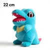 A blue plush toy of a Pokemon character, likely Totodile, is shown against a white background. The toy has its mouth open, revealing red inner mouth and white teeth. It has a yellow bib-like marking on its chest and a pink tail. Produktbild-Vorschau