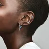 Close-up of a person's ear adorned with multiple silver earrings, including a feather charm with a blue stone. Voir les images du produit