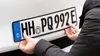 A person is attaching a license plate to a car. Náhled obrázku produktu